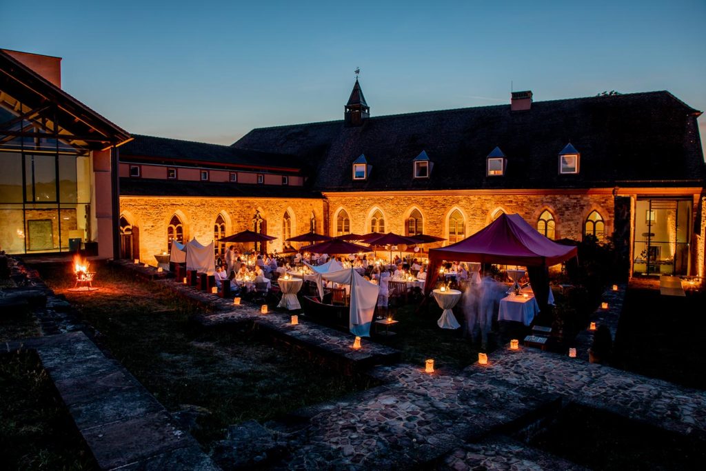 Abendliche Hochzeitsfeier im Klosterinnenhof des Hotel Kloster Hornbach mit festlich gedeckten Tischen, Kerzenlicht und historischer Klosterarchitektur.